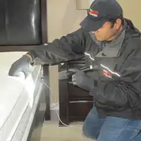 Bed bug inspection technician checking a mattress and bed frame for signs of infestation in Cambridge, MA