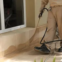 General pest control technician spraying exterior perimeter around a home in Cambridge, MA