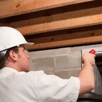Termite inspection technician checking a basement wall and framing for termite activity in Cambridge, MA